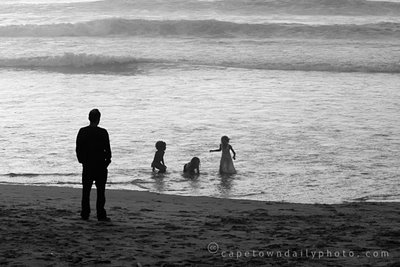 Dad watching kids play in the sea